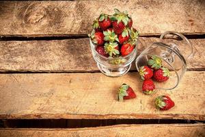 fragole in un bicchiere su un tavolo di legno foto