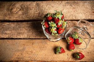 fragole in un bicchiere su un tavolo di legno foto