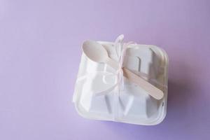 un' bento torta scatola con un' di legno cucchiaio sta chiuso su un' viola sfondo foto