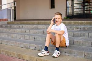 il ragazzo è seduta su il passaggi e parlando su il Telefono foto