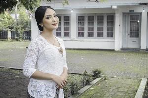 un' giovane indonesiano donna con un' contento riuscito espressione indossare un' bianca kebaya. di Kartini giorno concetto. foto