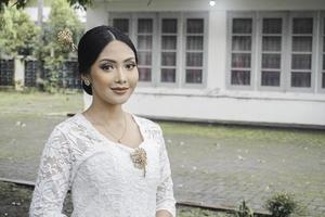 un' giovane indonesiano donna con un' contento riuscito espressione indossare un' bianca kebaya. di Kartini giorno concetto. foto