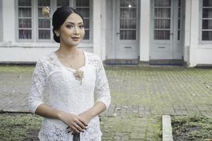 un' giovane indonesiano donna con un' contento riuscito espressione indossare un' bianca kebaya. di Kartini giorno concetto. foto