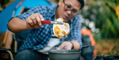 ritratto di asiatico viaggiatore uomo bicchieri frittura un' gustoso fritte uovo foto