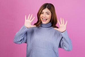 ritratto di contento giovane donna puntamento su con dito numero dieci isolato al di sopra di rosa sfondo foto