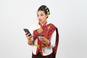 ritratto di bellissimo tailandese donna nel tradizionale capi di abbigliamento in posa con smartphone e credito carta foto