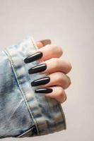 mano di un' giovane ragazza con nero manicure su Chiodi foto