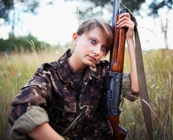 giovane bellissimo ragazza con un' fucile da caccia foto
