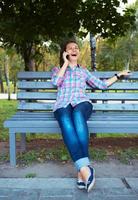 un' ritratto di un' sorridente bellissimo donna nel un' parco parlando su il Telefono foto