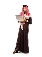 giovane sorridente arabo con il computer portatile isolato su bianca foto