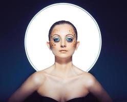 affascinante ritratto di giovane bellissimo ragazza con grande blu occhi, lussureggiante ciglia e luminosa d'oro trucco foto