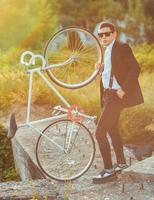 giovane elegante tipo con bicicletta all'aperto foto