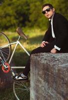 giovane elegante tipo con bicicletta all'aperto foto