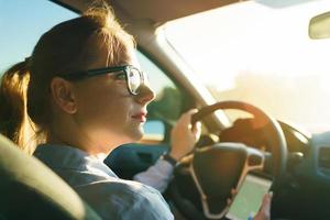 contento donna usi un' navigatore nel un' smartphone mentre guida un' auto foto
