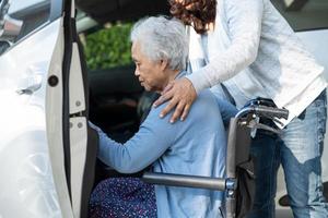 badante Aiuto e supporto asiatico anziano donna seduta su sedia a rotelle preparare ottenere per sua auto per viaggio nel vacanza. foto