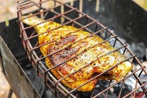 grigliato pesce su il griglia, cucinato su fuoco, barbecue foto