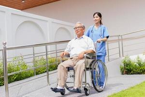 assistenza infermieristica casa cura concetto. asiatico giovane infermiera Disabilitato anziano uomo. infermiera, cura casa e anziano uomo con invalidità nel un' sedia a rotelle nel un al di fuori medico facilità. foto