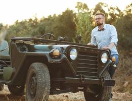 giovane elegante uomo con bicchieri e arco cravatta vicino il vecchio stile suv foto