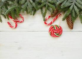 Natale confine con abete albero rami con coni e caramella canna su bianca di legno tavole pronto foto