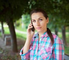 ritratto di un' donna nel un' parco parlando su il Telefono foto