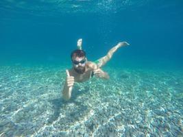 giovane barba uomo con maschera immersione nel un' pulito acqua foto