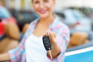 donna in piedi vicino un' convertibile con chiavi nel mano - concetto di acquisto un' Usato auto o un' noleggio auto foto