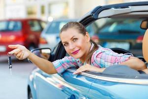 giovane bella donna seduta nel un' convertibile auto con il chiavi nel mano foto