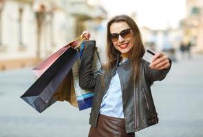 bellissimo donna con shopping borse e credito carta nel il mani su un' strada foto