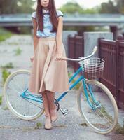 giovane donna bellissima, elegantemente vestita con la bicicletta. bellezza, moda e stile di vita foto