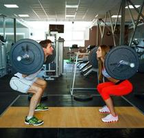 atletico uomo e donna con manubrio fare squat nel il Palestra foto