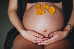 aspettativa di il bambino. un' incinta donna seduta con giocattolo piedi. maternità concetto. foto