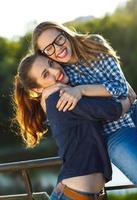 Due giocoso ragazze avendo divertimento all'aperto a tramonto leggero foto