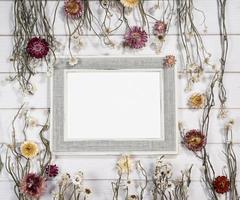 superiore Visualizza di vuoto foto telaio con asciutto colorato fiori al di sopra di un' bianca di legno tavolo