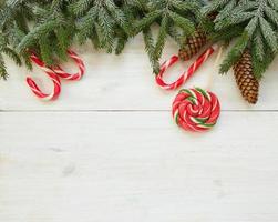 Natale confine con abete albero rami con coni e caramella canna su bianca di legno tavole foto