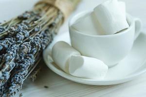 marshmallow nel un' tazza e lavanda su un' bianca di legno foto