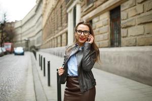 donna d'affari a piedi giù il strada mentre parlando su inteligente Telefono foto