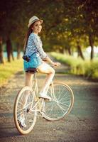 bello giovane donna nel un' cappello equitazione un' bicicletta all'aperto. attivo persone foto