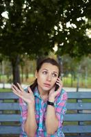 ritratto di un' donna nel un' parco su un' panchina parlando su il Telefono foto