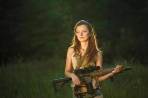 giovane bellissimo ragazza con un' fucile da caccia nel un all'aperto foto