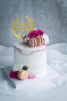 carino nudo torte decorato con macaron e rosa fiore su bianca stoffa foto