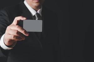 uomo d'affari nel nero costume e grigio cravatta mostrando grigio carta foto