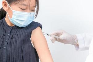 medico iniettare vaccinazione nel braccio di asiatico poco ragazza, sana medico e vaccino concetto foto