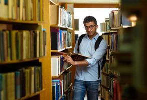 alunno lettura libro fra il scaffali nel il biblioteca foto