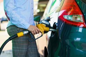 donna riempimenti benzina in il auto a un' gas stazione foto