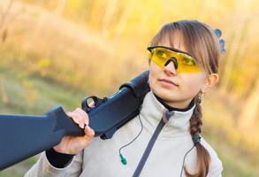 giovane bellissimo ragazza con un' fucile da caccia foto