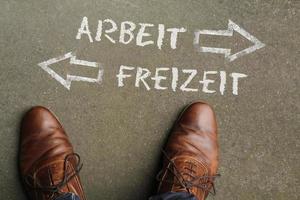 opera vita equilibrio - il parole Arbeit e Freizeit - Tedesco per opera e scorta tempo - scritto su il pavimento con frecce puntamento nel di fronte indicazioni foto