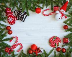 Natale confine con abete albero rami, Natale decorazioni e caramella canna su bianca di legno tavole foto