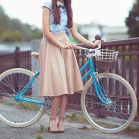 giovane donna bellissima, elegantemente vestita con la bicicletta. bellezza, moda e stile di vita foto
