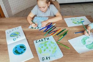 bambini disegnare il pianeta terra con matite e pennarello penne su album lenzuola per terra giorno a loro casa tavolo. foto