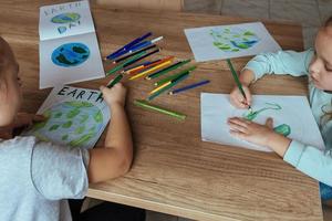 bambini disegnare il pianeta terra con matite e pennarello penne su album lenzuola per terra giorno a loro casa tavolo. foto